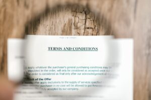 Magnifying glass focusing on terms and conditions document on wooden surface.